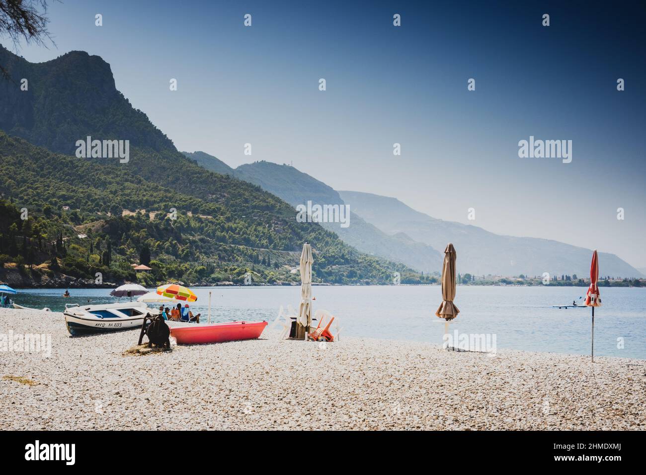 Closed umbrellas with boats on beach against clear sky on sunny day Stock Photo