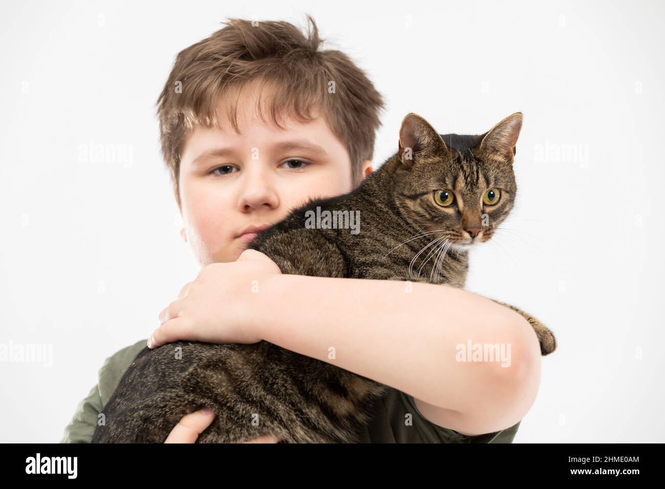A boy holds a shecat in his arms and hugs her. Closeup view Stock