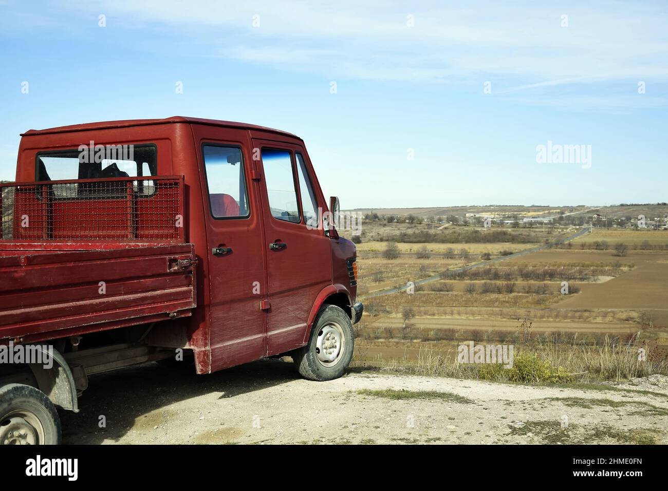 Moldova, Old Orhei, November 2019: The little red truck stop at the edge of the cliff. Blue sky. View of the road and autumn fields. Selective focus. Stock Photo