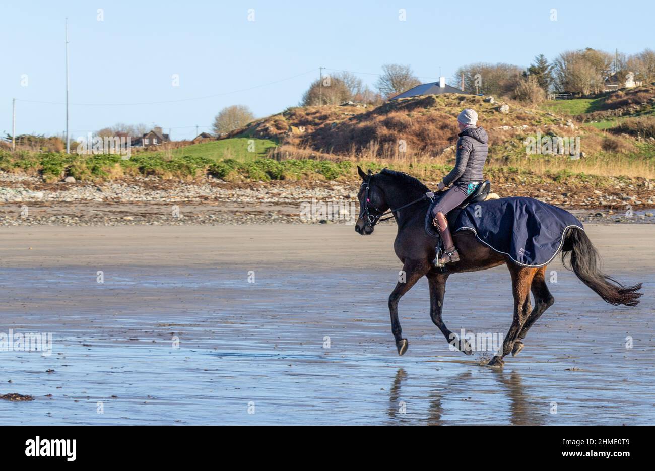 Woman in Silhouette or backlit riding horse through surf Stock Photo