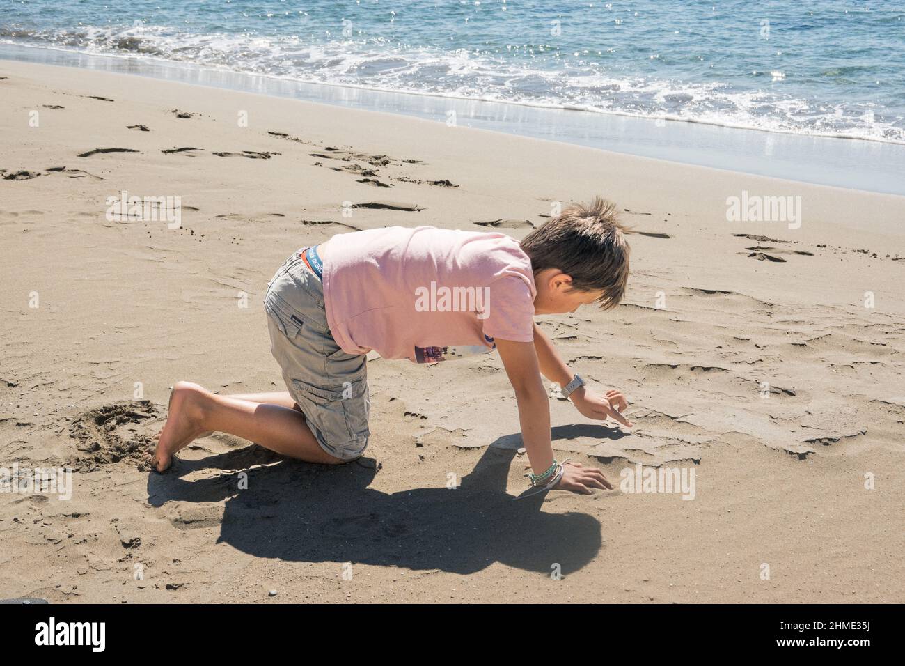Little boy drawing in sand on beach near sea Stock Photo