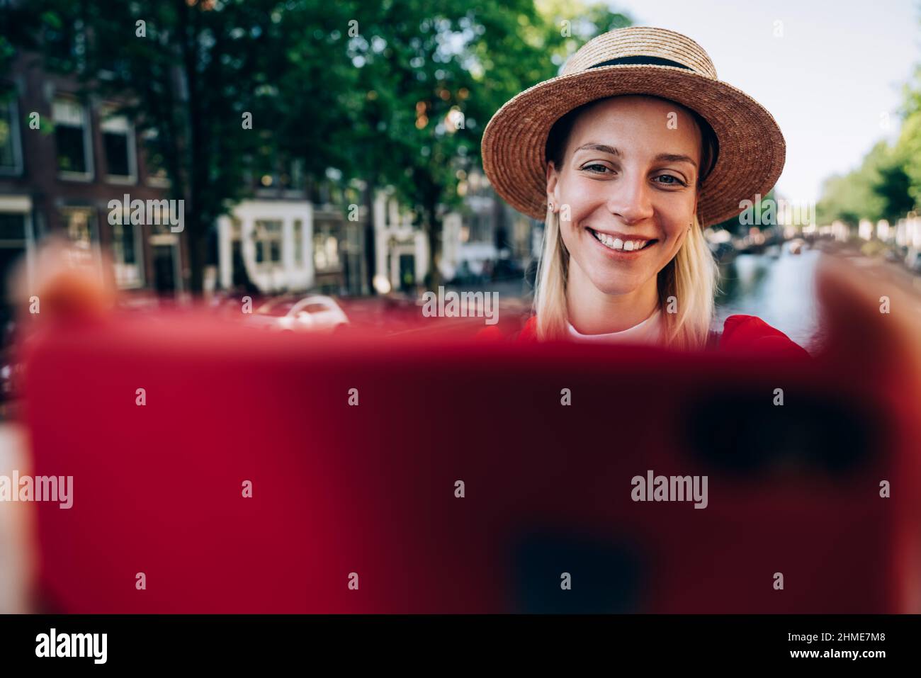 Excited woman in hat taking selfie in city Stock Photo