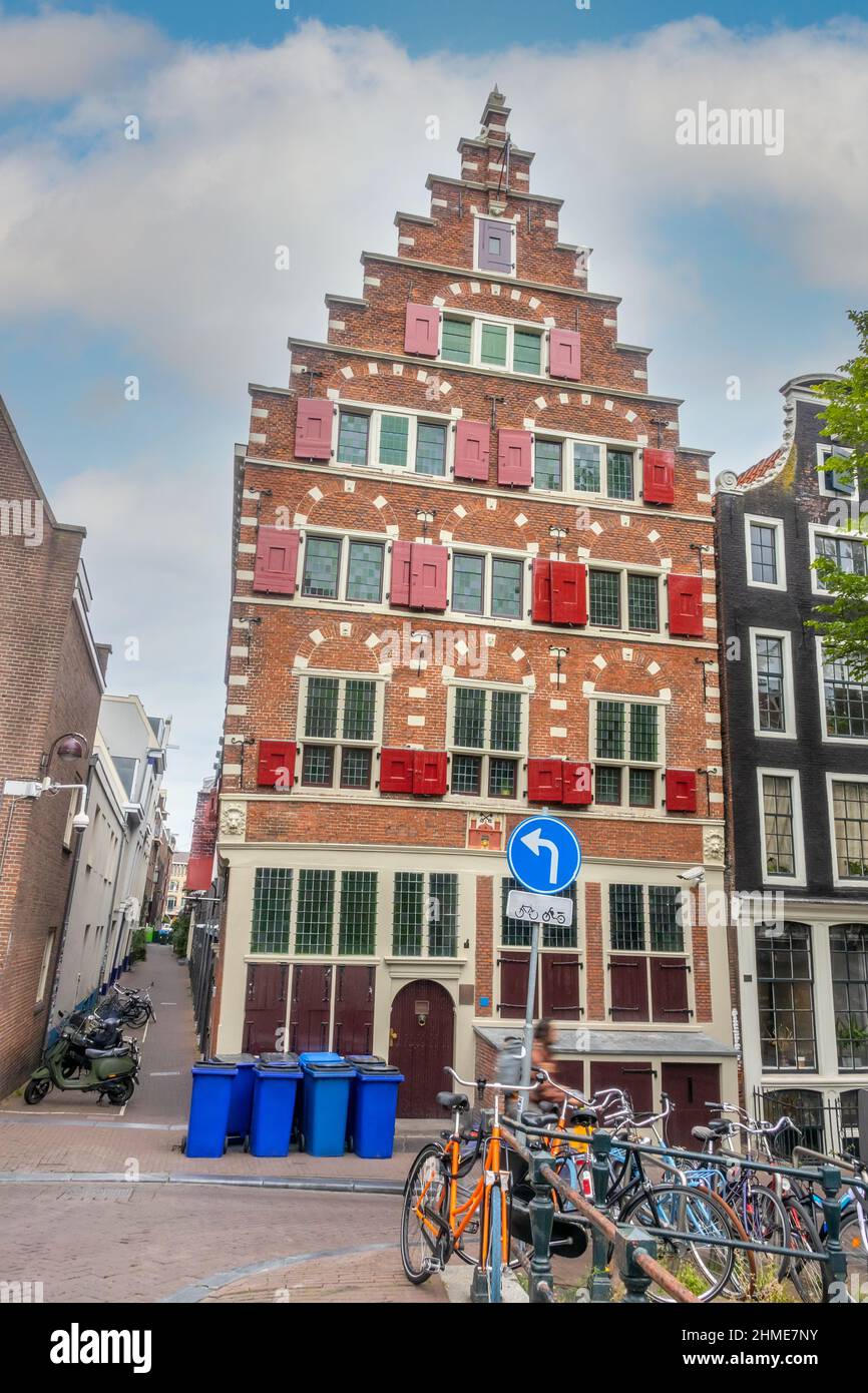 Netherlands. Narrow streets of Amsterdam with parked bikes and scooters. Typical Dutch house with red shutters on the windows Stock Photo
