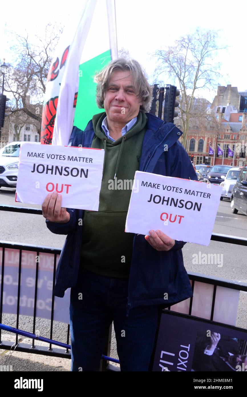 London, UK, 9th February, 2022. An anti brexit protester holds a placard critical of UK Prime Minister Boris Johnson and calling for him to leave office across the road from the House of Commons. Stock Photo