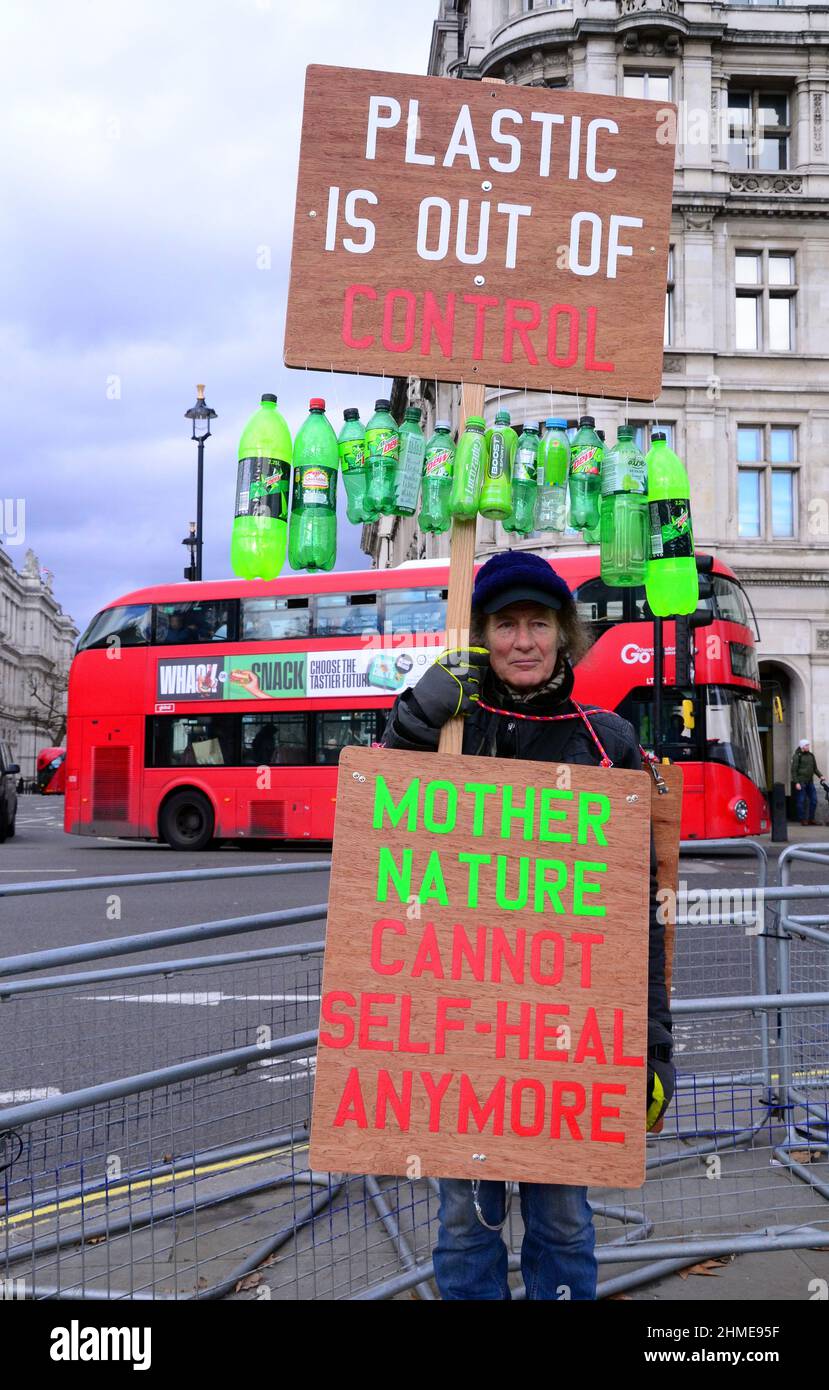 London, UK, 9th February, 2022. A person holds a solo protest outside the House of Commons, holding placards saying our use of plastic is out of control and mother nature cannot self heal any more. Stock Photo