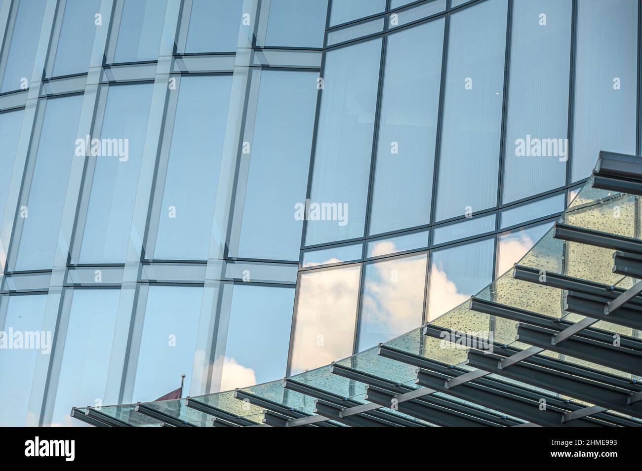 Glass facade of an office building with reflections of the blue sky and ...