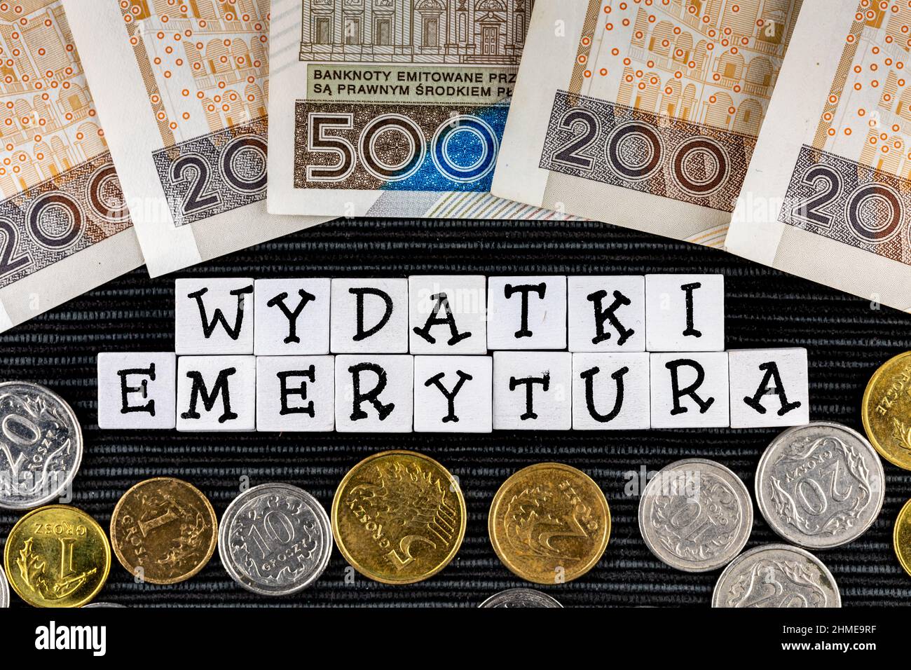 The wording 'wydatki emerytury' translated as 'expenses pensions' and many Polish coins and banknotes on the black background. New taxation rules in P Stock Photo