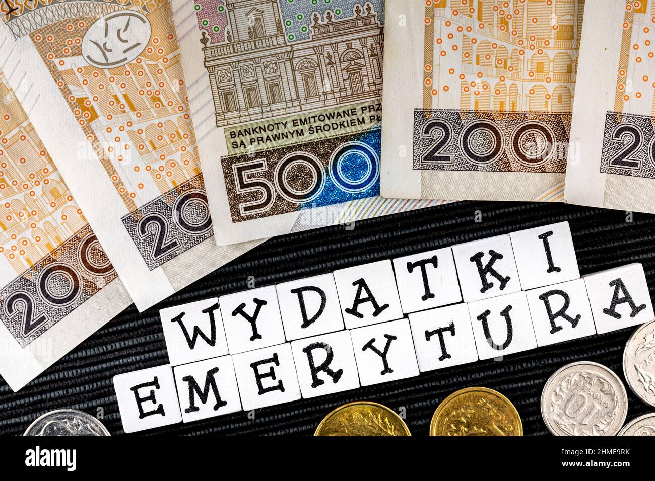 The wording 'wydatki emerytury' translated as 'expenses pensions' and many Polish coins and banknotes on the black background. New taxation rules in P Stock Photo