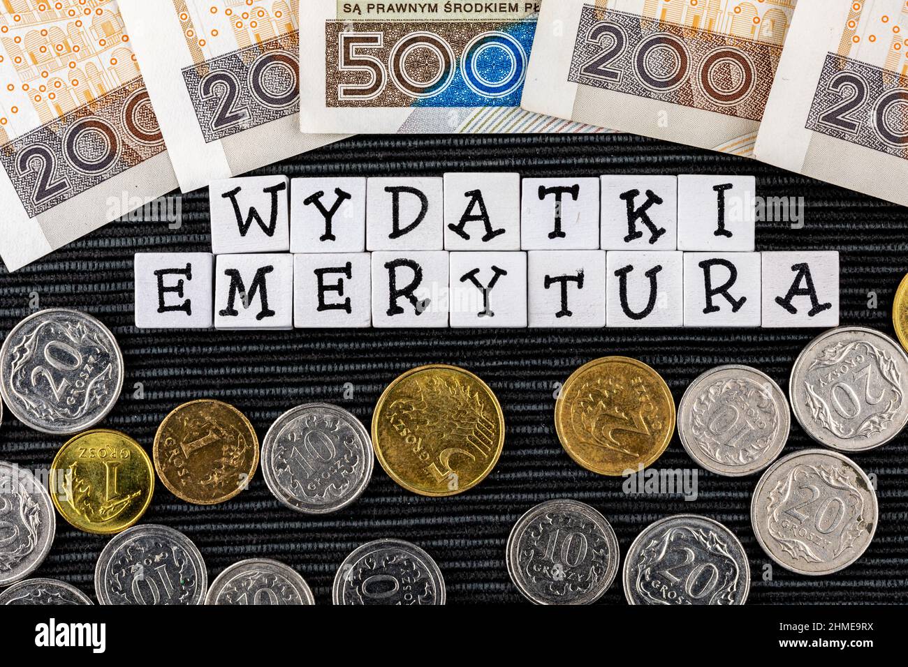 The wording 'wydatki emerytury' translated as 'expenses pensions' and many Polish coins and banknotes on the black background. New taxation rules in P Stock Photo