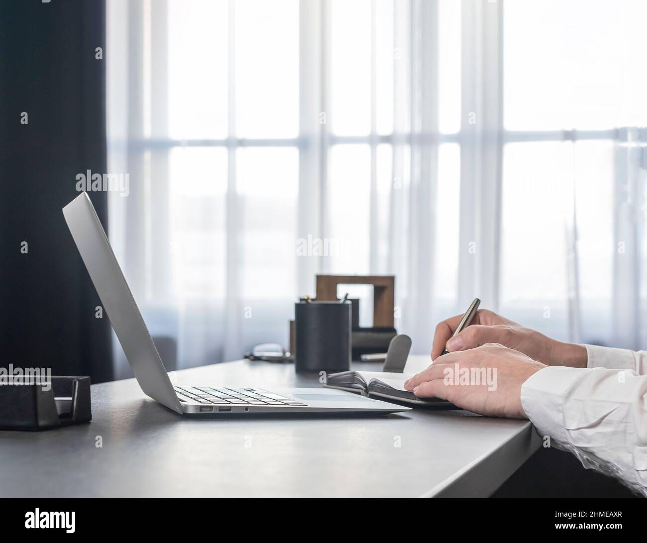 Hands taking notes, writing in planner, notebook at office desk with ...