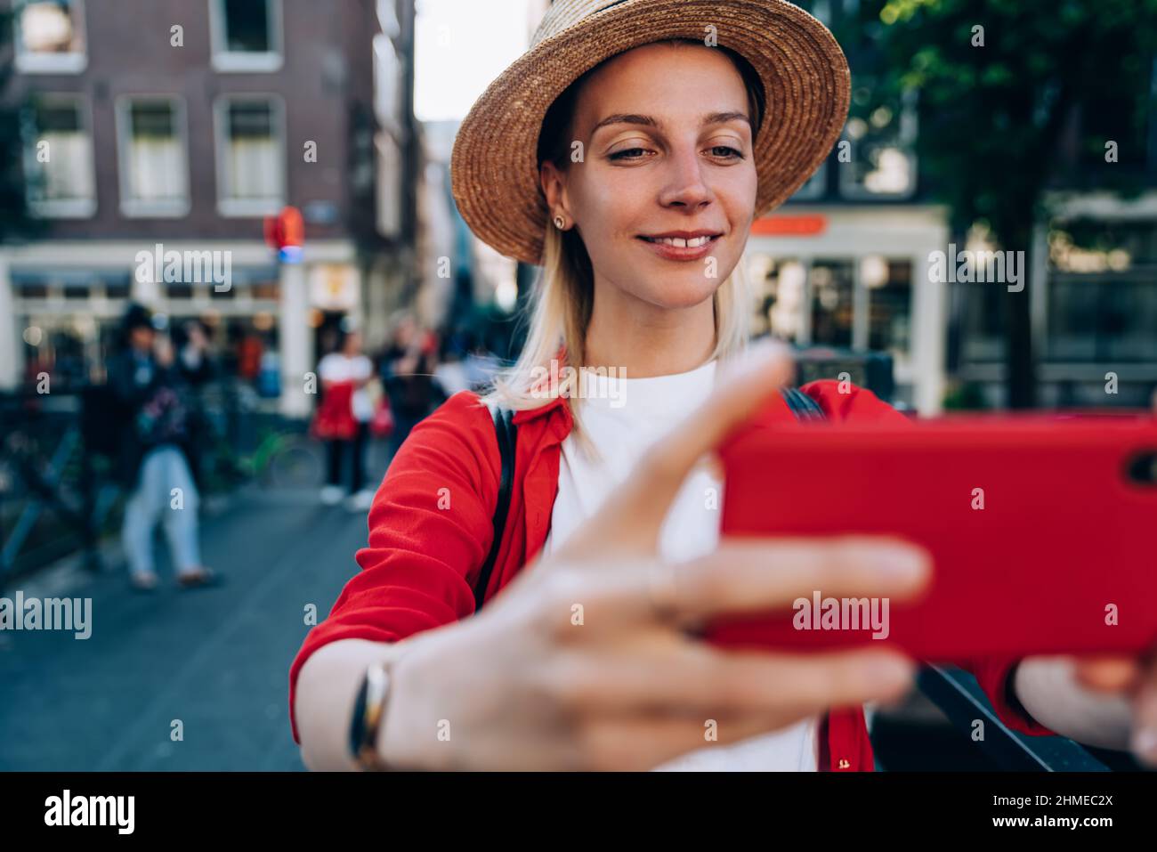 Smiling woman taking selfie on smartphone on city street Stock Photo