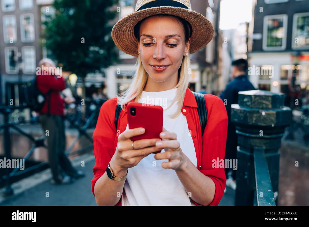 Smiling female traveler messaging on smartphone during tour Stock Photo
