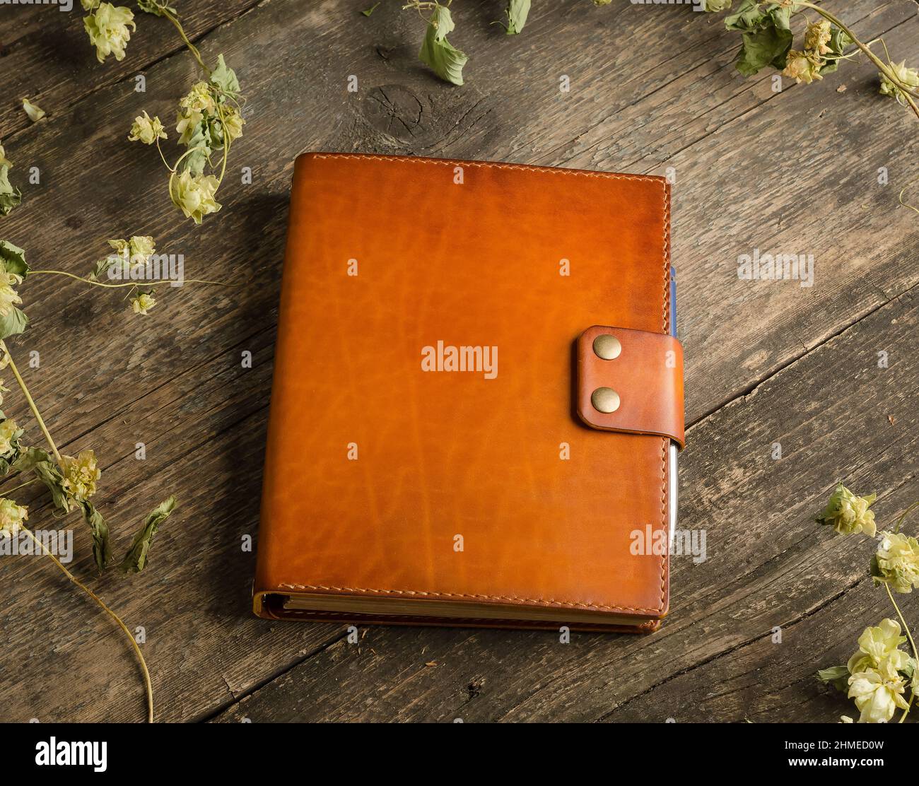 Handmade leather men's wallet in brown-orange color on an old vintage wooden background. Stock Photo