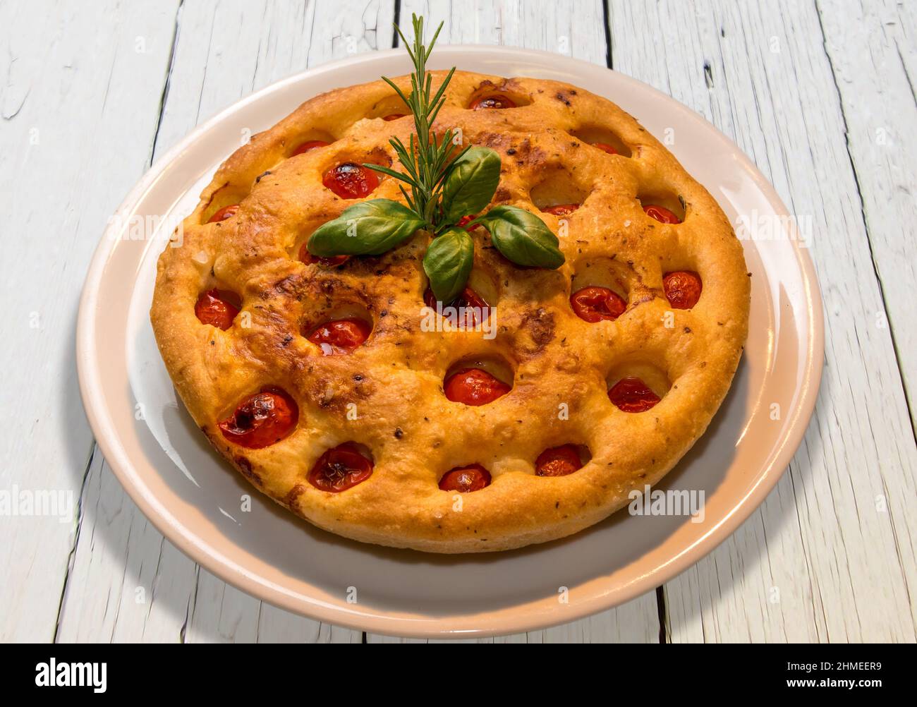 Apulian focaccia, typical italian Bari pizza made with a dough of durum wheat flour and potatoes  with cherry tomatoes on top. In white plate on white Stock Photo