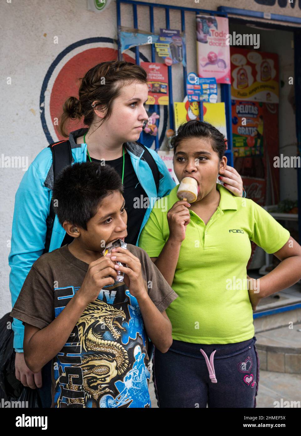 An NGO worker stands behind two Nicaraguan deaf children eating ice cream in Jinotega, Nicaragua. Stock Photo