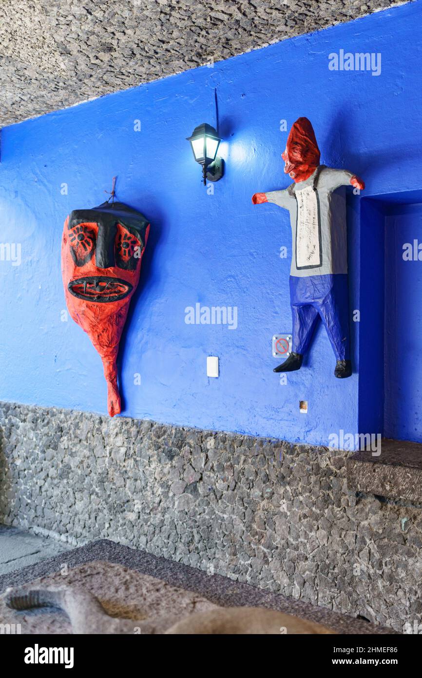 Two paper mache indigenous sculptures hang on a blue wall in the Frida Kahlo museum that was her house and studio. Stock Photo