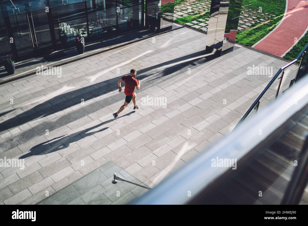 Anonymous fit sportsman running along sidewalk in city Stock Photo