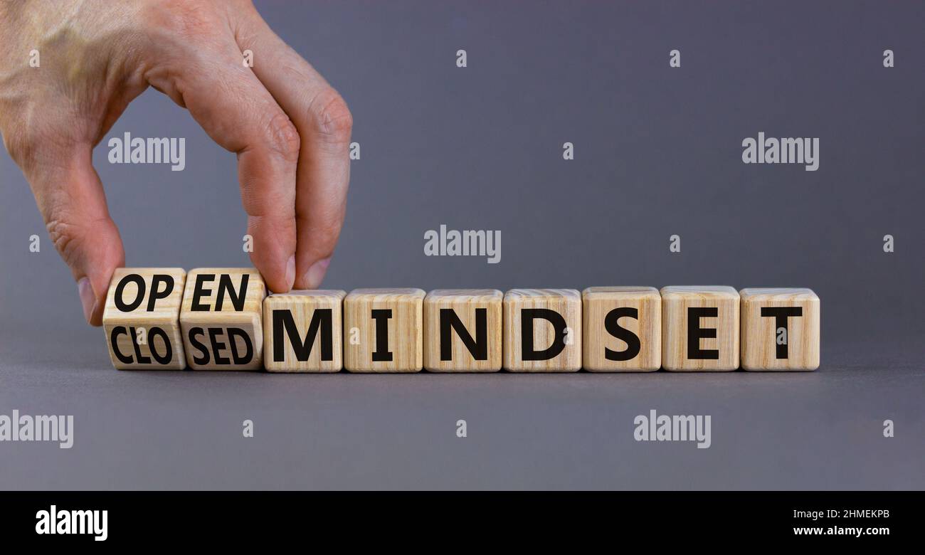 Open or closed mindset symbol. Businessman turns wooden cubes and changes concept words closed mindset to open mindset. Beautiful grey background, cop Stock Photo