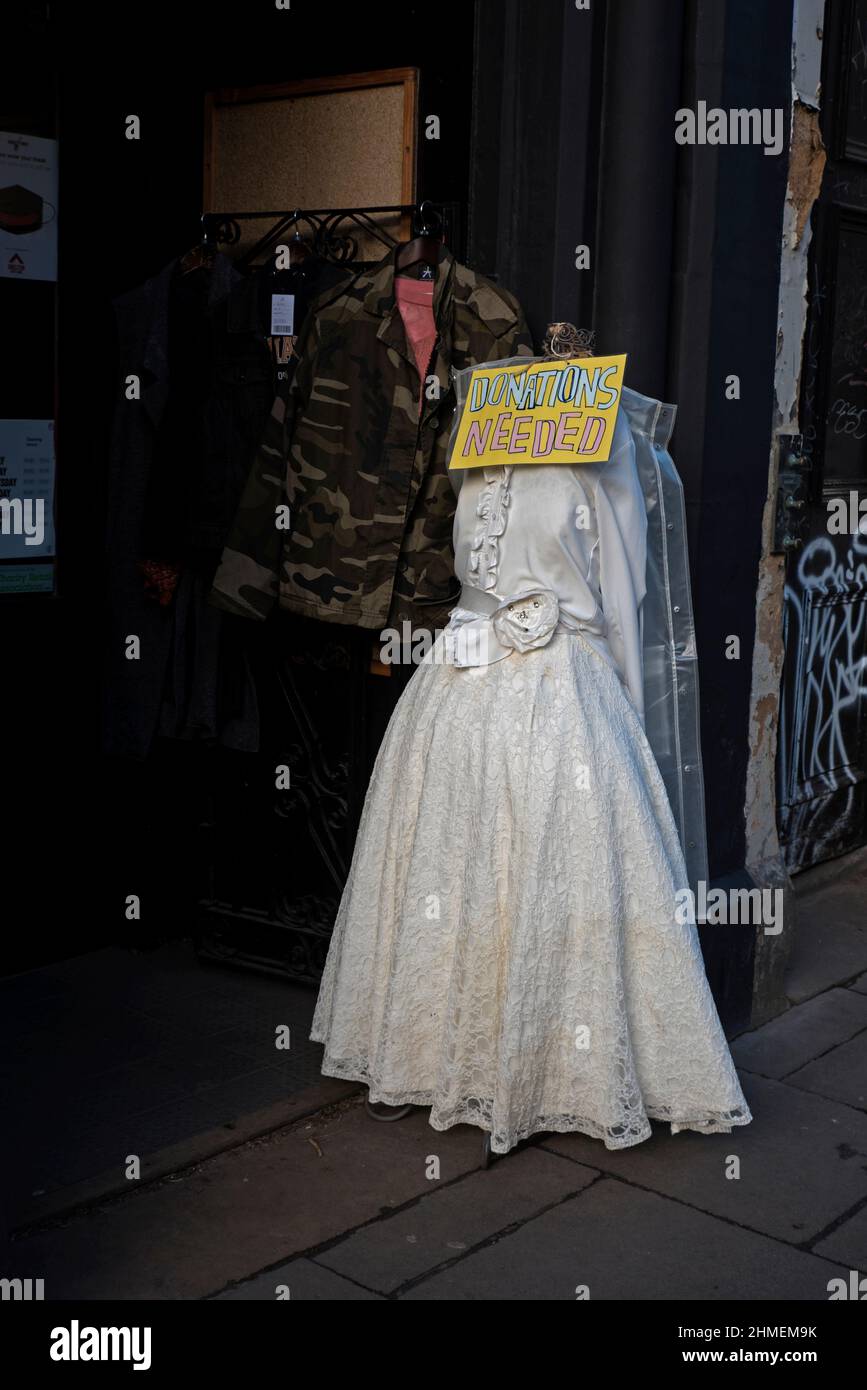 'Donations Needed' sign on a mannequin wearing a white dress outside a Shelter charity shop on Forrest Road, Edinburgh, Scotland, UK. Stock Photo