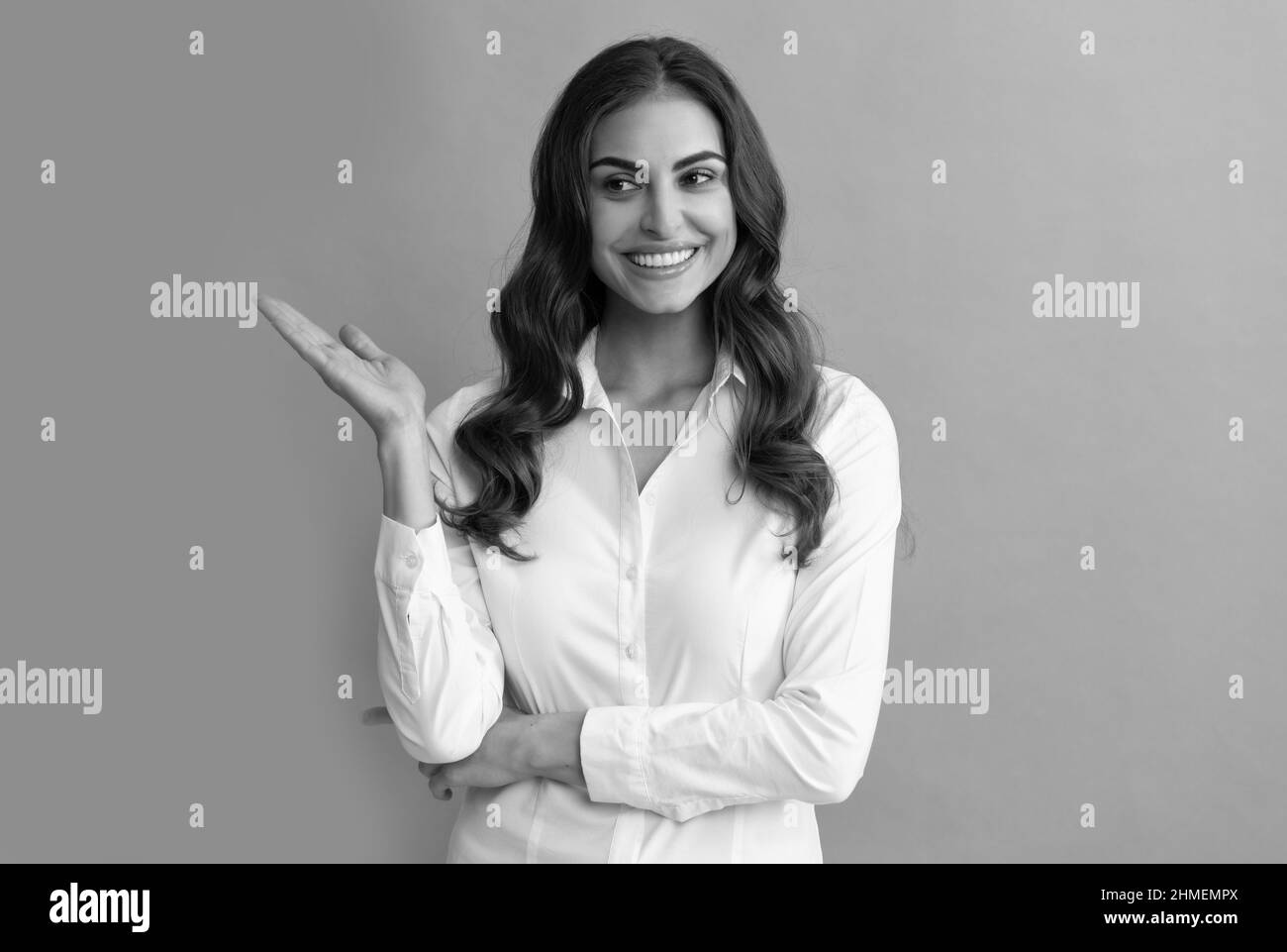 Happy professional woman manager show open hand for copy space grey background, presenting product Stock Photo