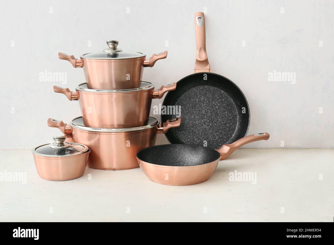 Set of copper kitchen utensils on table against white background Stock
