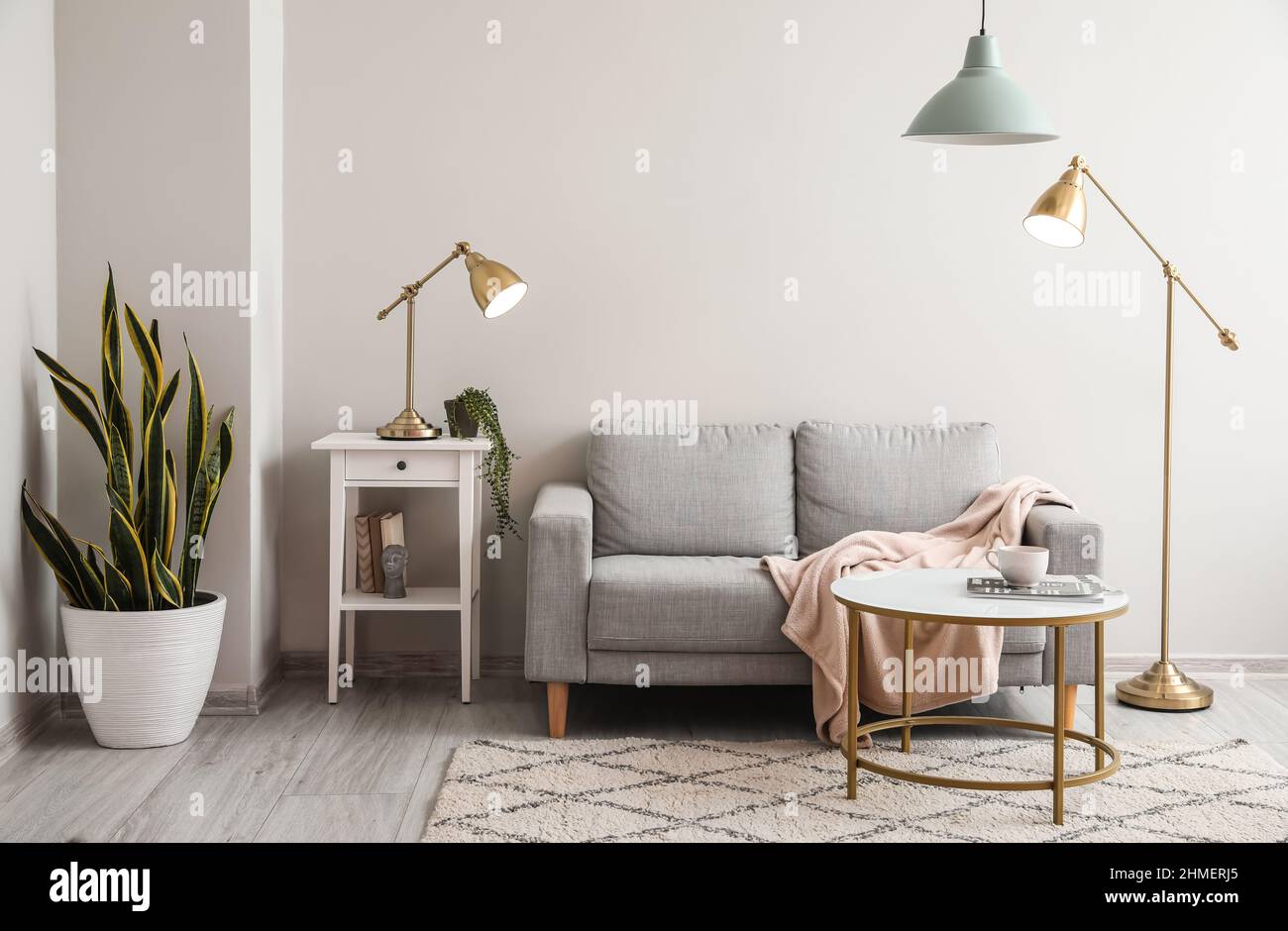 Interior of light living room with grey sofa, table and lamps Stock ...