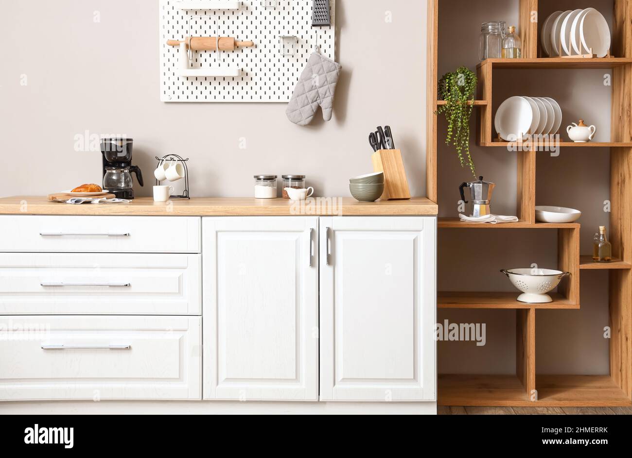 Interior of light kitchen with wooden shelving unit and pegboard Stock ...