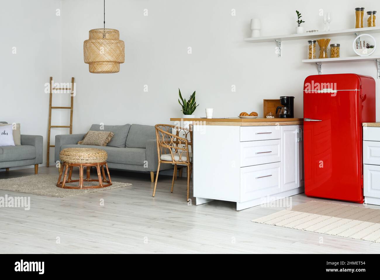 Interior of light kitchen with white counters, red fridge and sofas