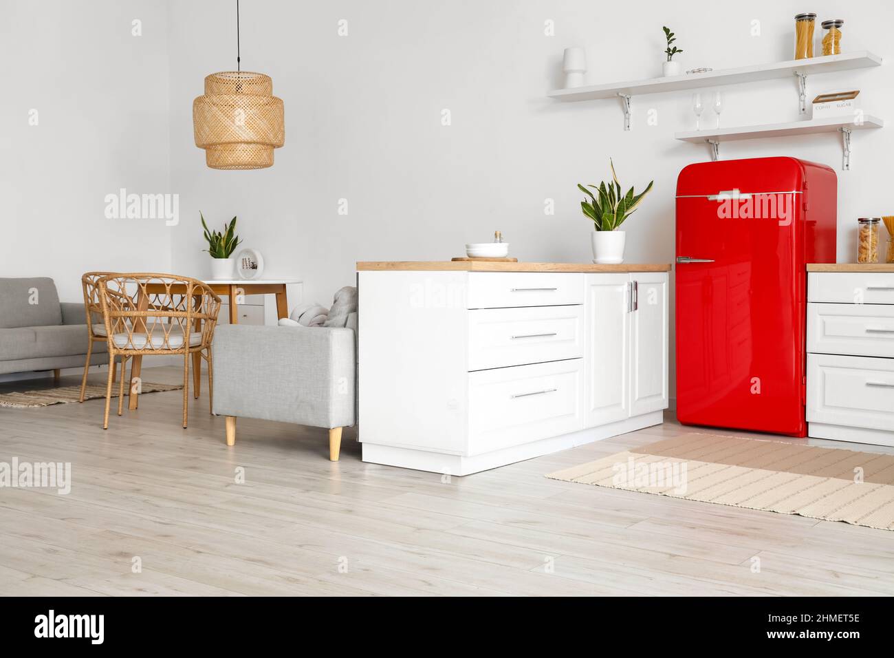 Interior of light kitchen with white counters, red fridge and dining ...