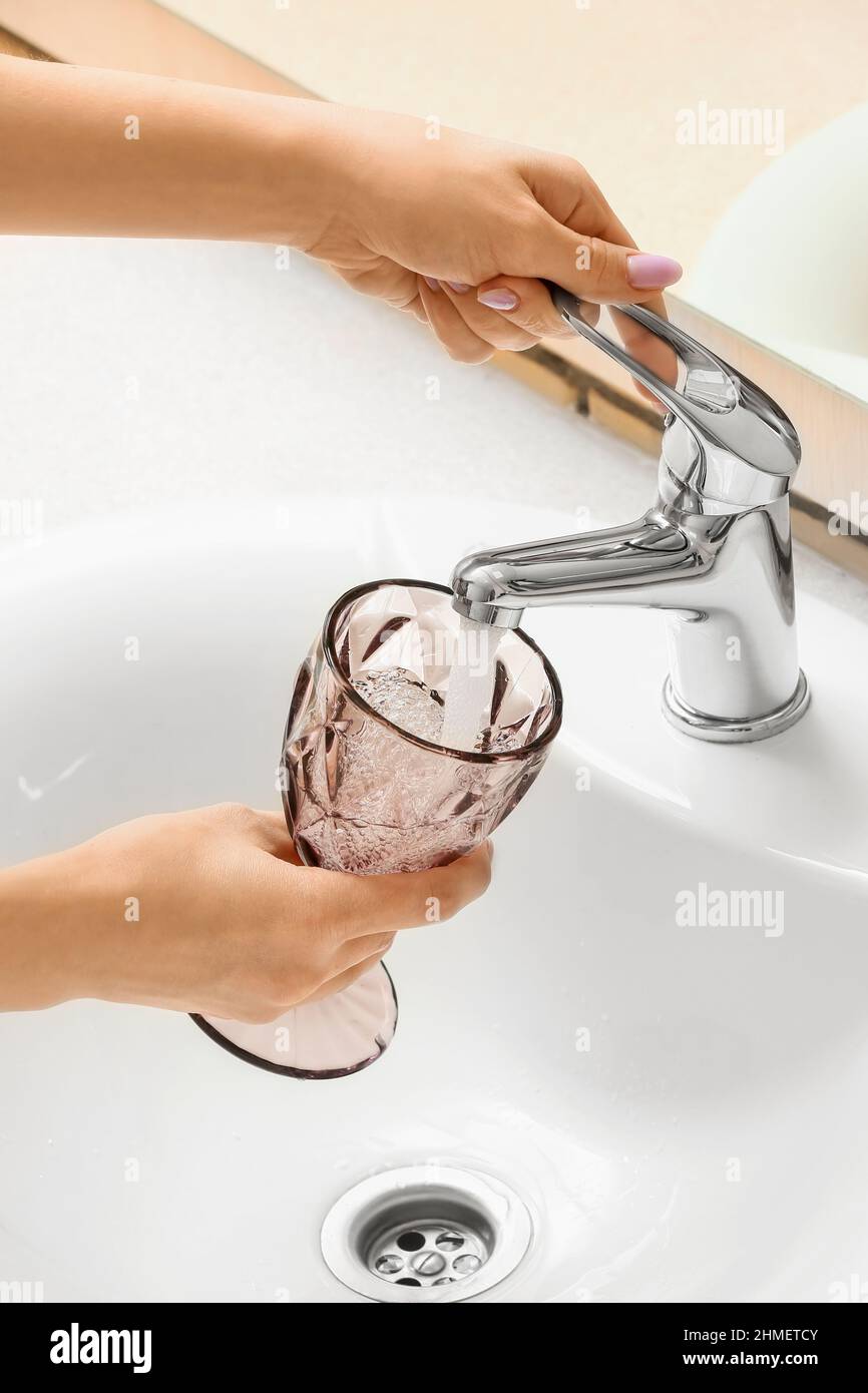 Woman with glass turning off tap in bathroom, closeup Stock Photo Alamy