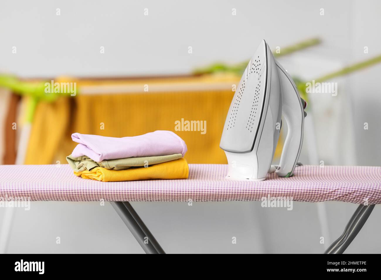 Stack of clothes and electric iron on board Stock Photo