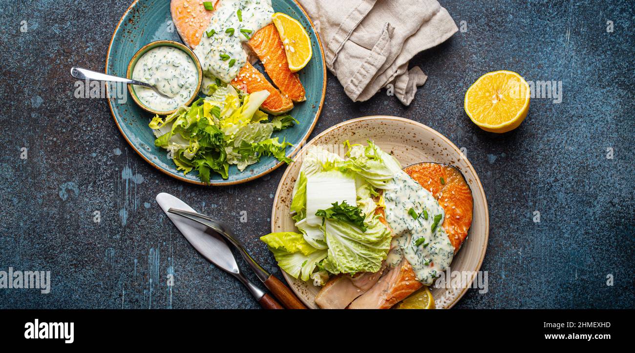 Healthy food meal grilled salmon steaks with dill sauce and salad leafs on two plates Stock Photo