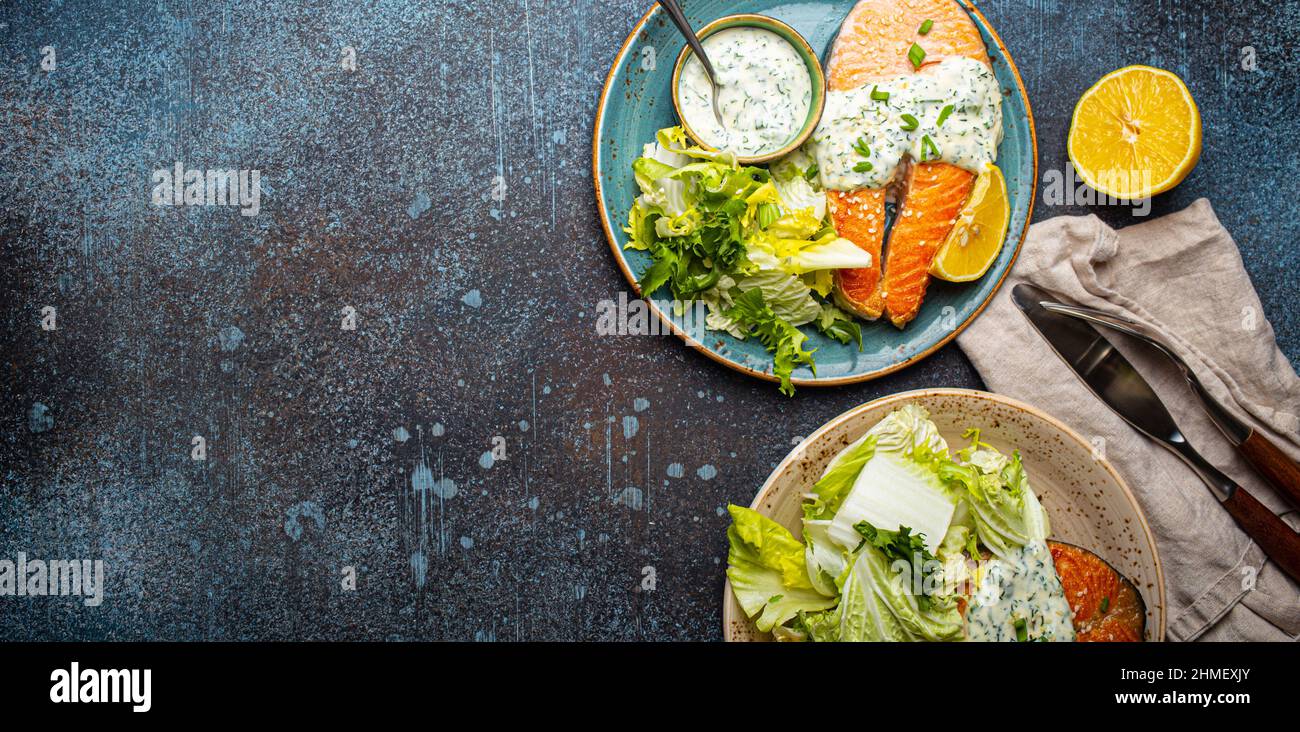 Healthy food meal grilled salmon steaks with dill sauce and salad leafs on two plates Stock Photo