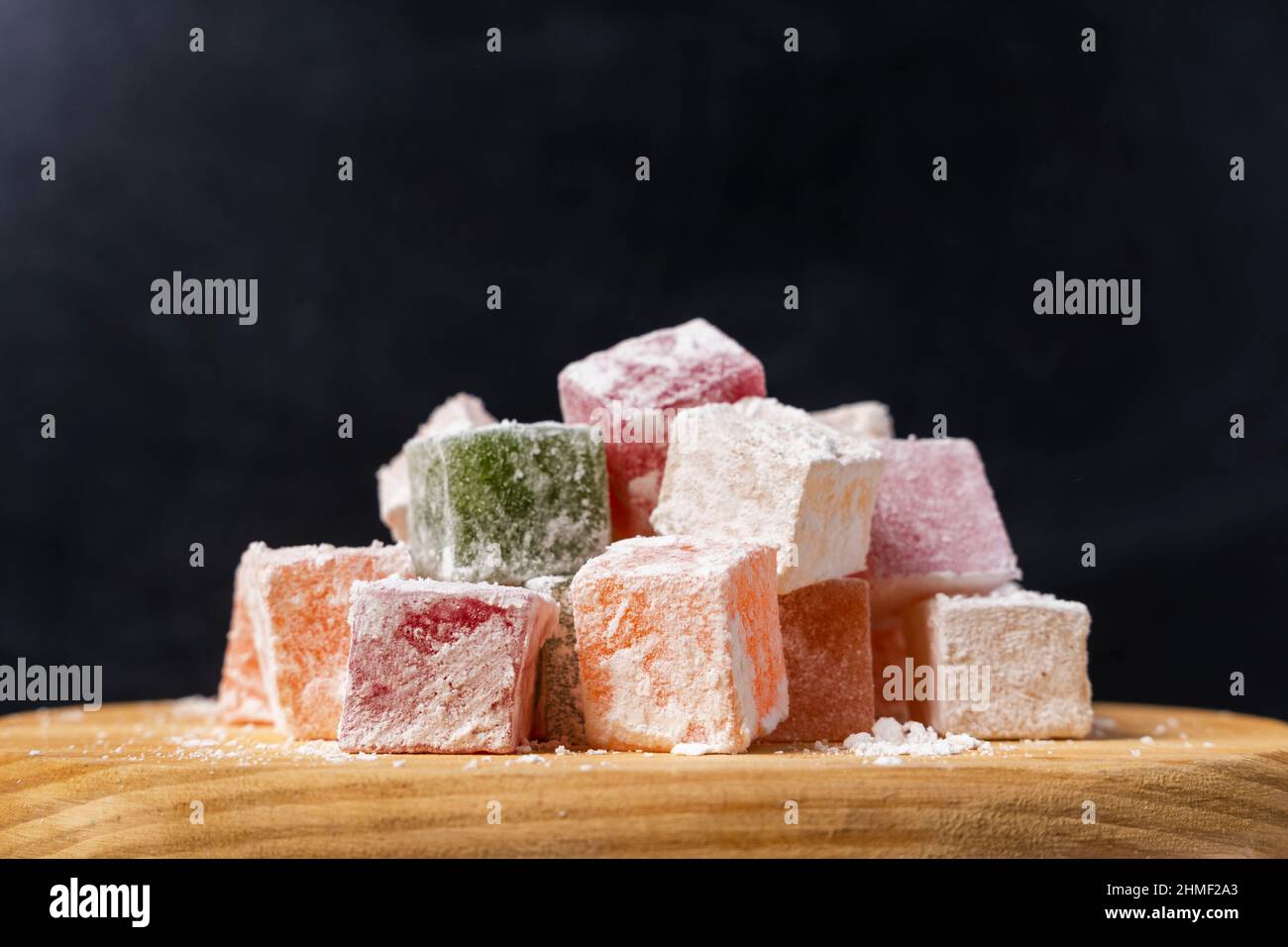 Sweet delicious colored lukum, Turkish delight with powdered sugar on a black background. Delicious natural delicacy, dessert Stock Photo