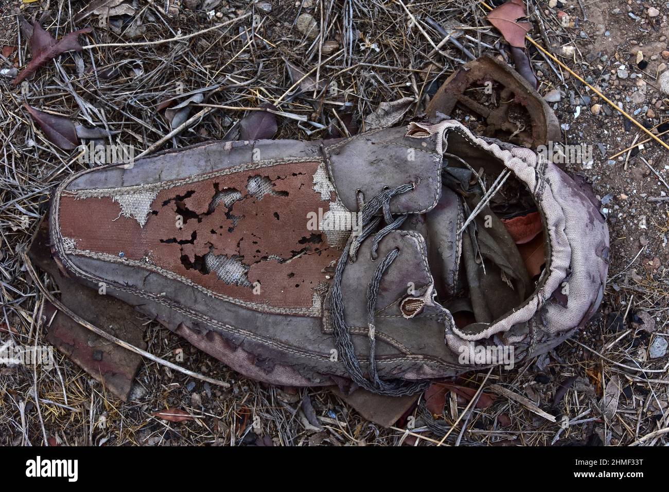 Men's low shoe on the floor, decrepit leather shoe standing on wall