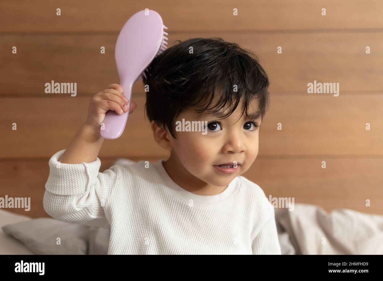 Adorable Hispanic 2 year old baby combing his hair after shower Stock