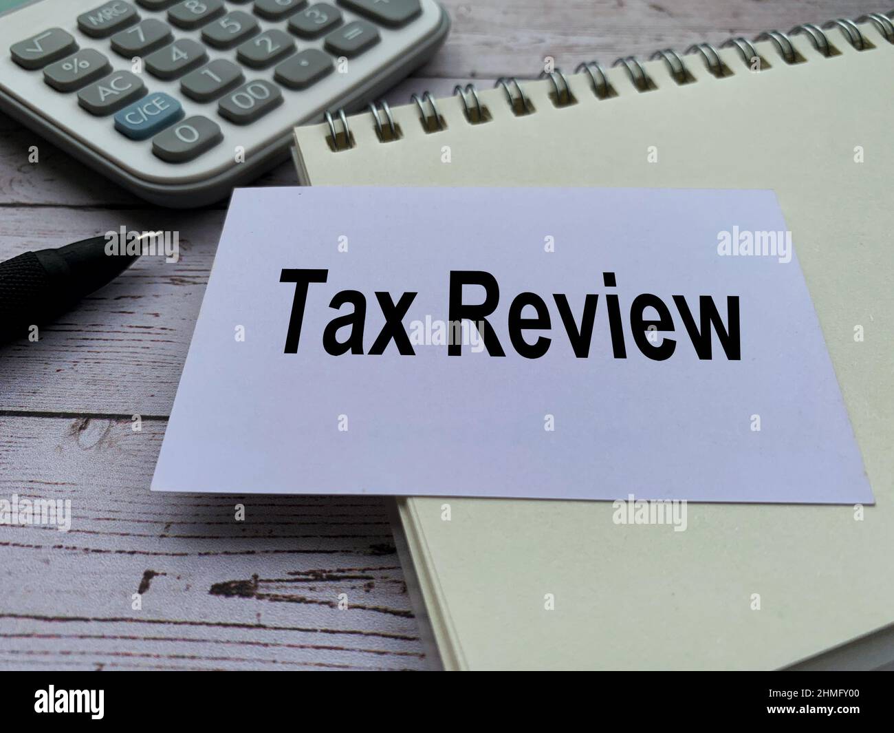Tax review text on small white card with notepad, pen and calculator