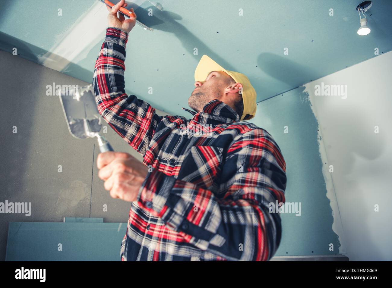 Caucasian Professional Interior Finishing Worker in His 40s Patching Room Ceiling. Apartment Remodeling Home Improvement Job. Stock Photo