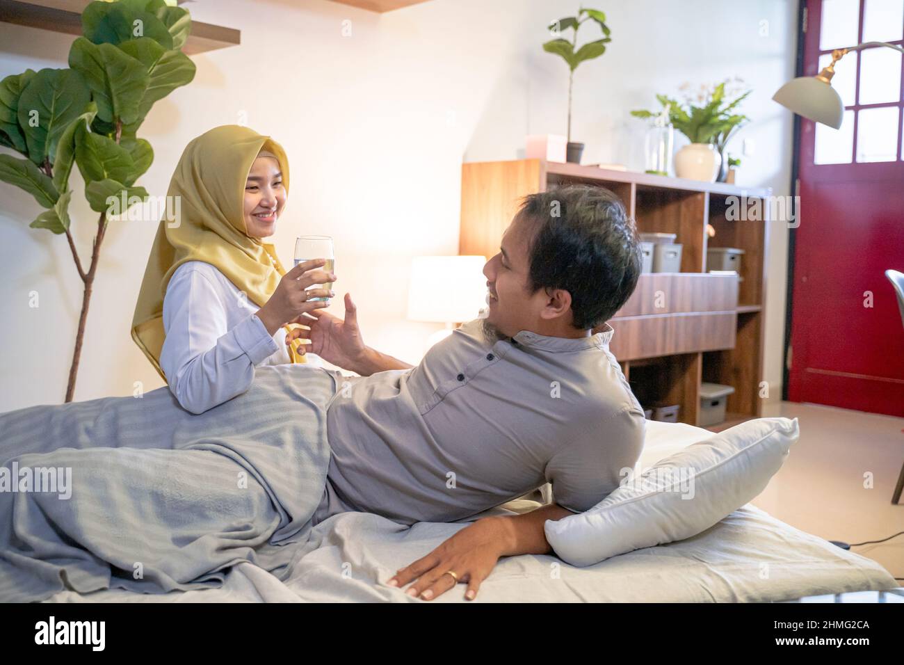 wife waking her husband up in the bed to have a breakfast Stock Photo