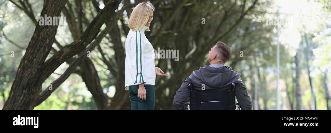 Young smiling woman walks in park with man in wheelchair Stock Photo ...
