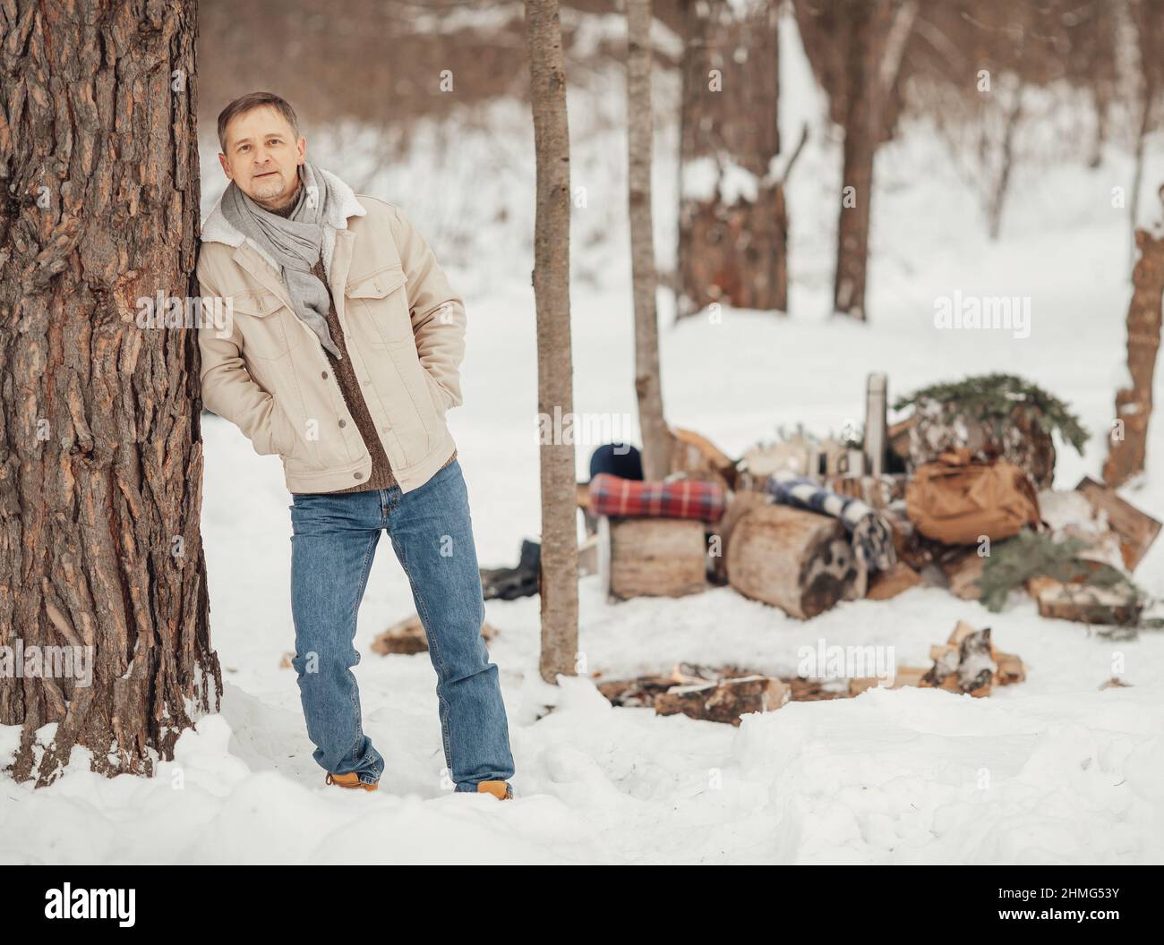 A brutal man in the winter forest by the fire drinking coffee Stock Photo