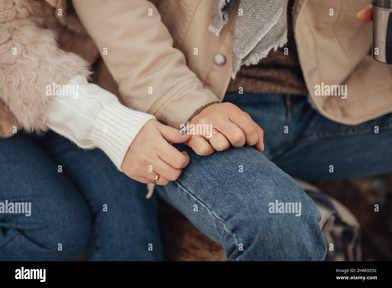 A couple in love, a man and a woman in a winter forest around a campfire drink coffee and give marshmallows Stock Photo