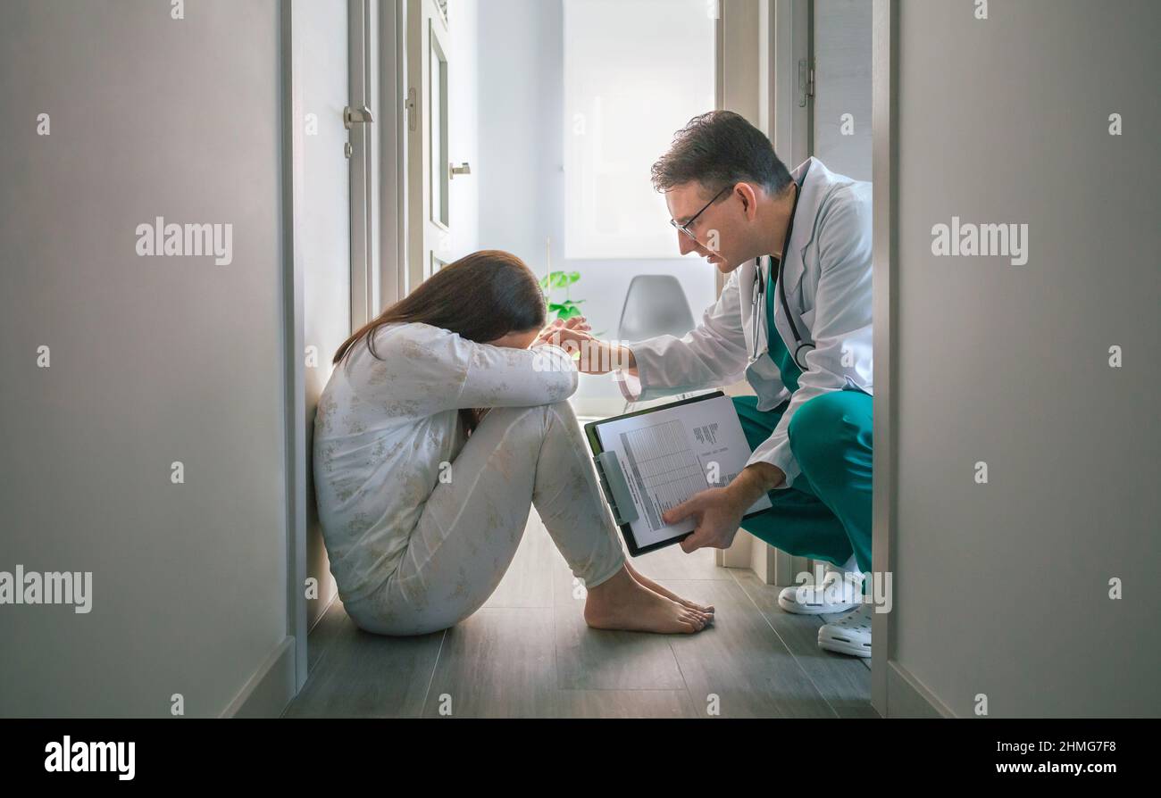 Psychiatrist trying to help with empathy a female patient with mental disorder who refuses help in a mental health center Stock Photo