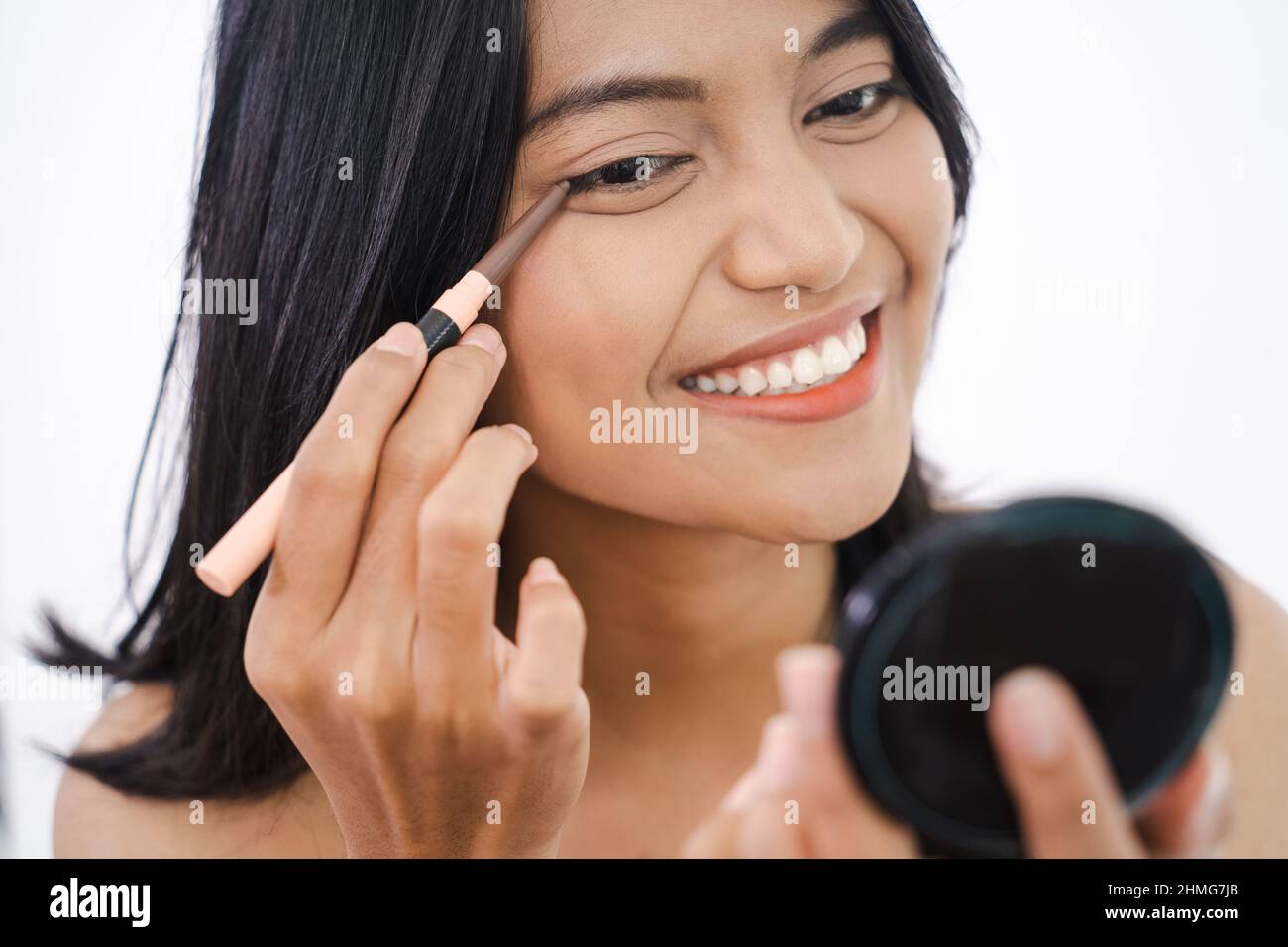 asian girl touching black eyeliner to her eyelid Stock Photo Alamy