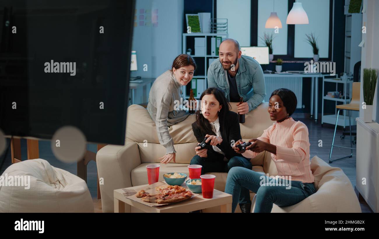 Multi ethnic group of people using joysticks to play video games on tv ...