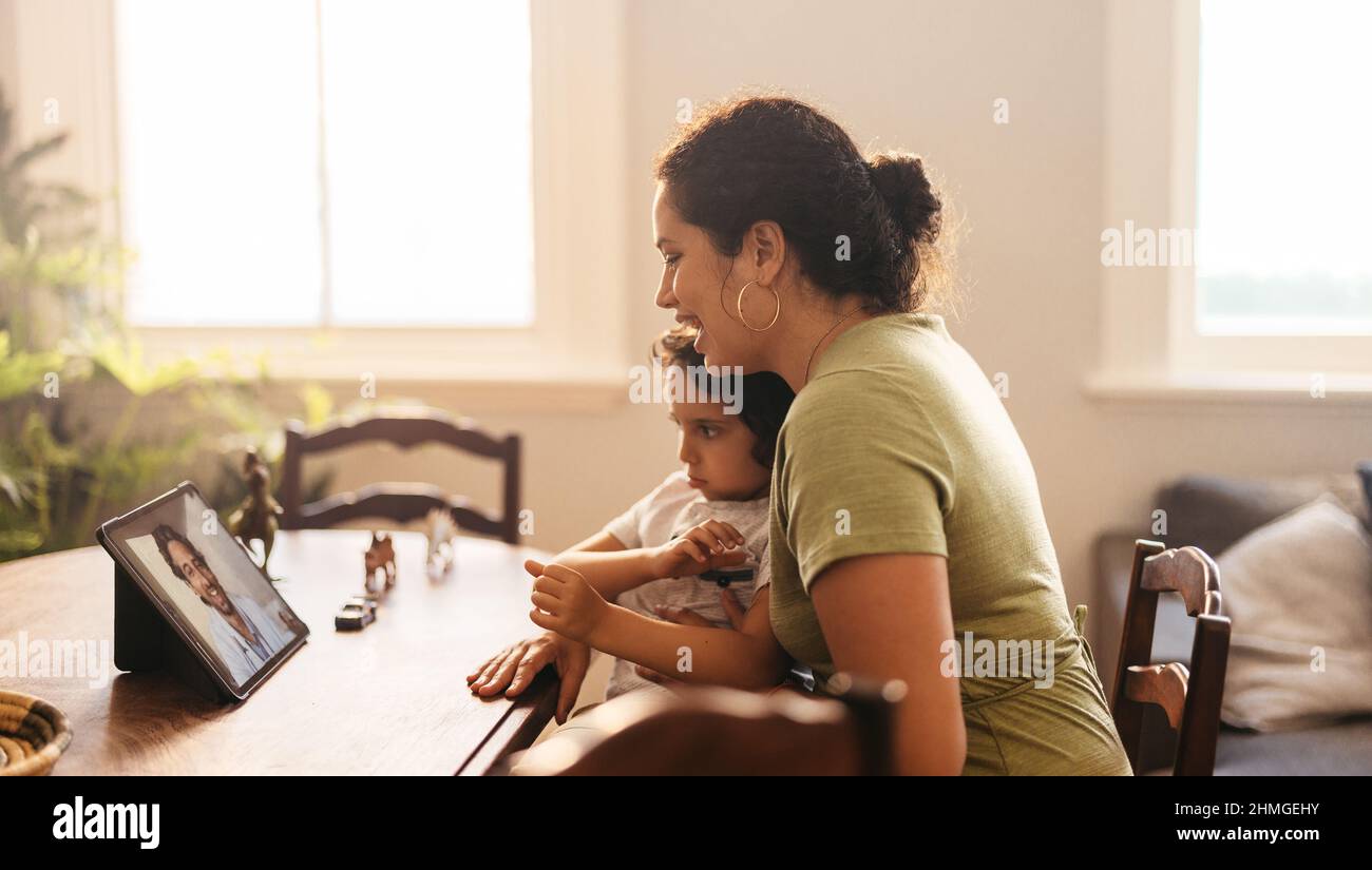 Young mother getting good news from her family doctor on a video call. Mother and son having an online consultation with their paediatrician. Loving y Stock Photo