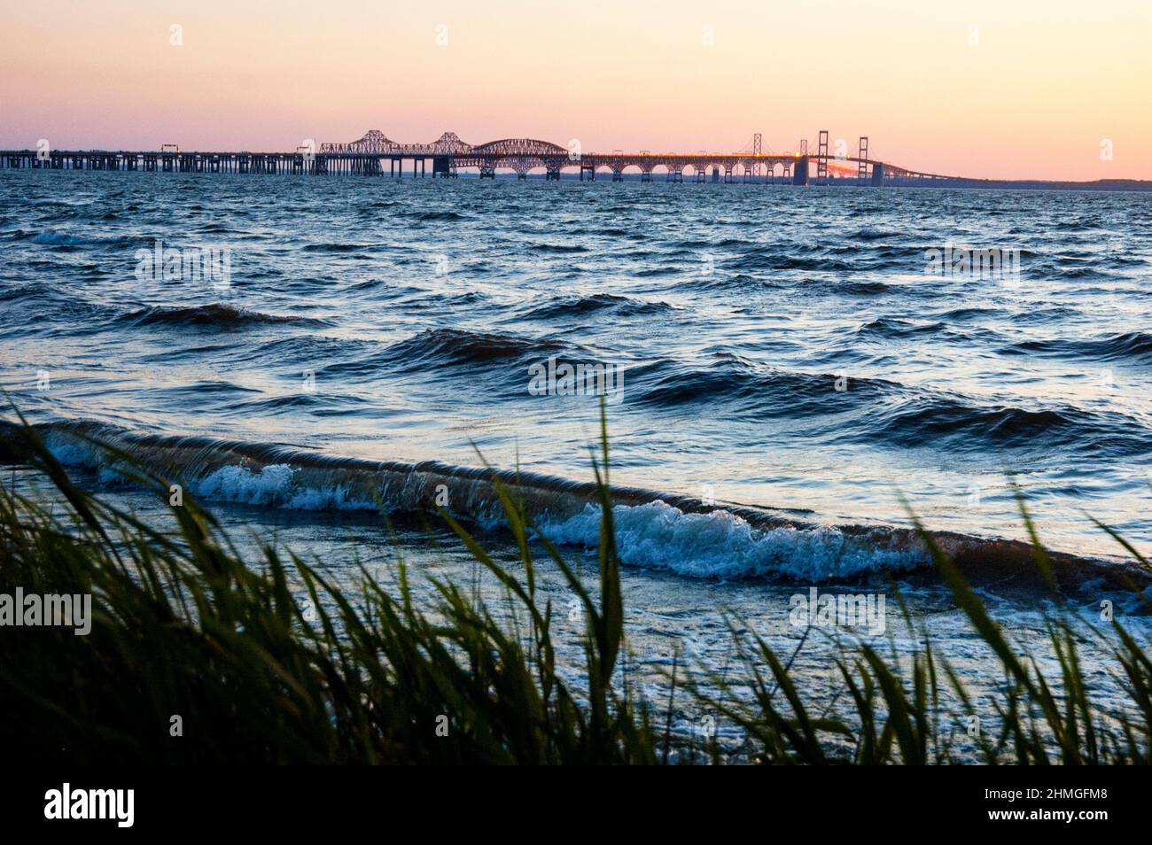 Eastern shoreline of the Chesapeake Bay at Terrapin Nature Park and sun setting over the parallel Bay Bridges in Maryland. Stock Photo