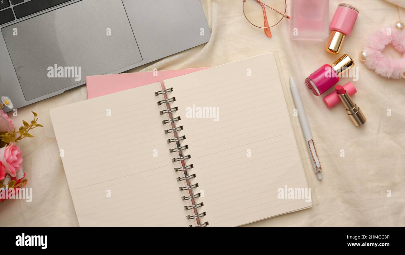 Female college student study table or workspace with pink accessories, laptop and empty pages of school spiral notebook. top view, flat lay Stock Photo