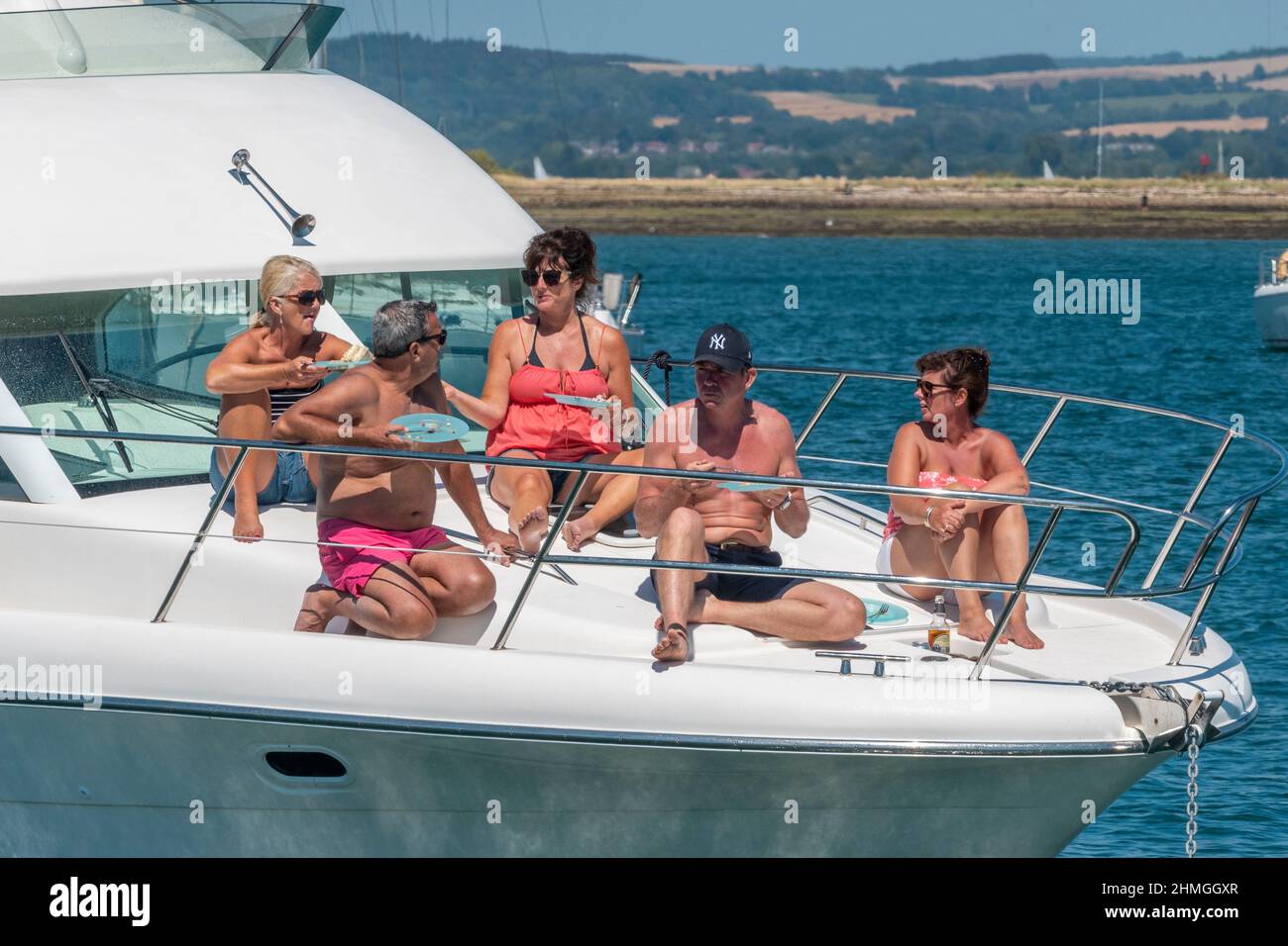 Group of people anchored at East Head, West Wittering, enjoying the good weather and lounging on the foredeck of their motorboat.West Sussex,England Stock Photo