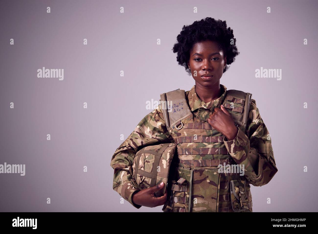 Studio Portrait Of Serious Young Female Soldier In Military Uniform Against Plain Background Stock Photo